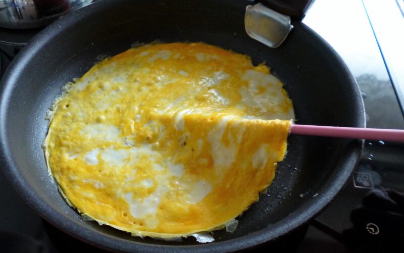 焼いた卵の下にシリコン菜箸がするっと入っていく様子を撮影した写真