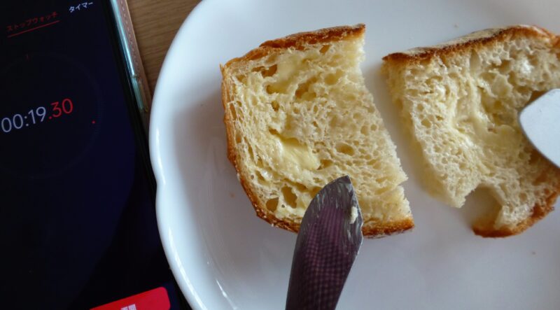 アルミスプーンでパンにバターを塗り終わった時間を計測した様子を撮影した写真