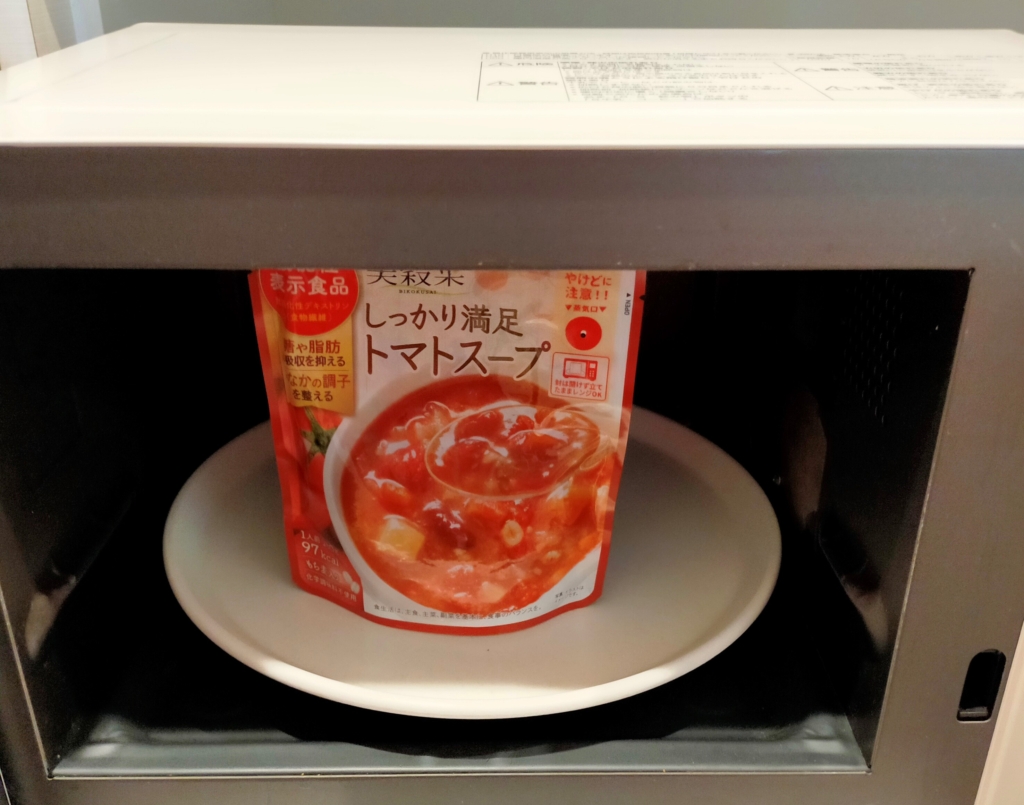 【しっかり満足トマトスープ】の封を切らずに電子レンジに立てて温めている様子を撮影した写真